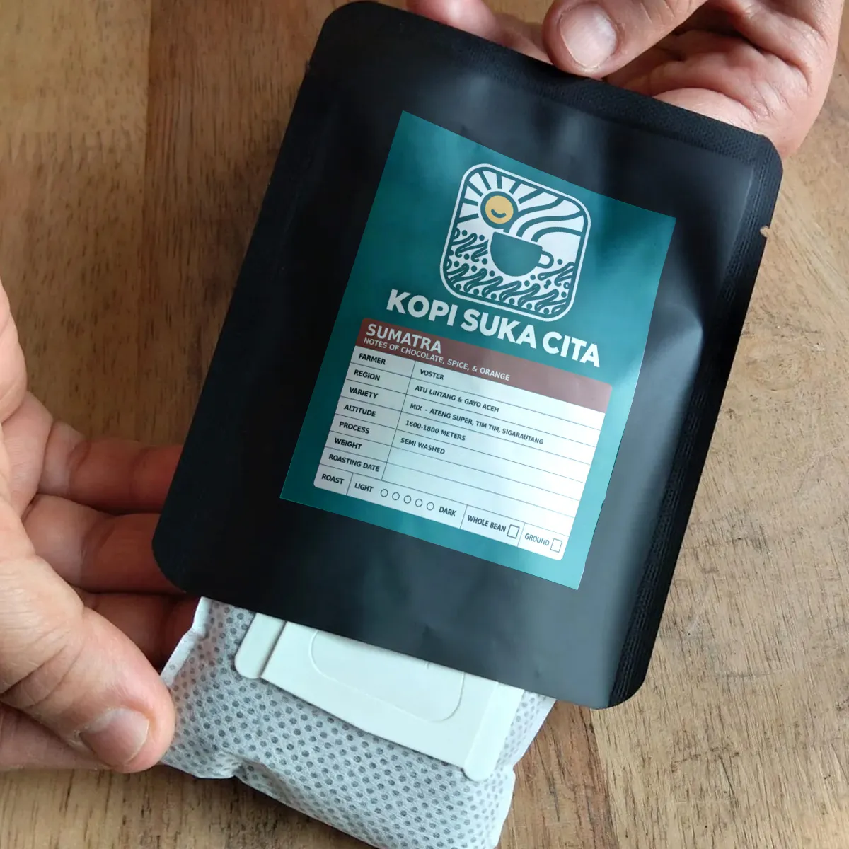 Holding a Kopi Suka Cita coffee pack alongside a single-brew drip bag