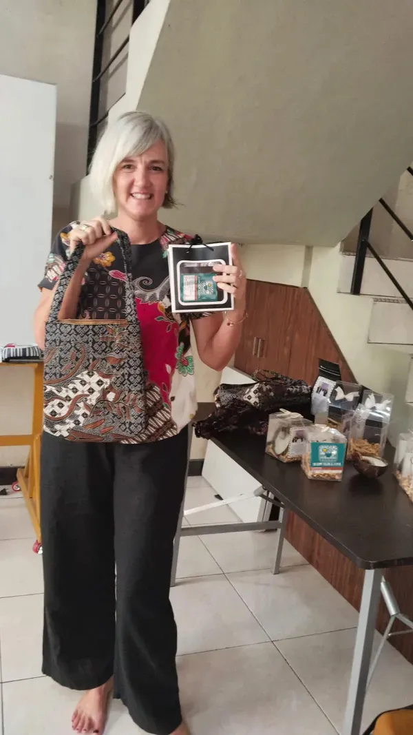 A customer holding a bag of Kopi Suka Cita coffee alongside handmade goods