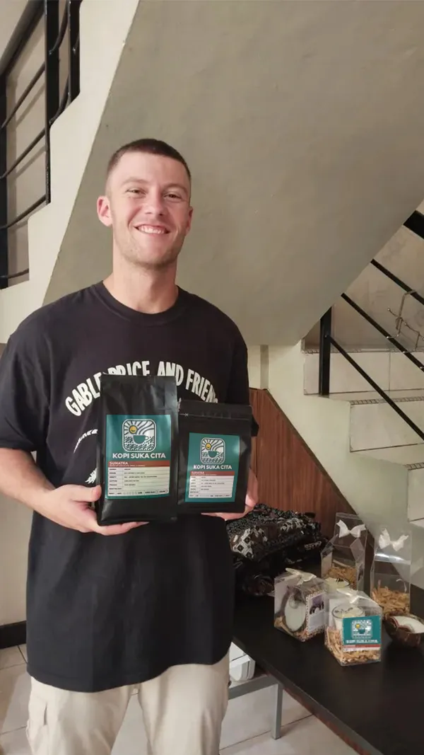 A customer holding two bags of Kopi Suka Cita coffee